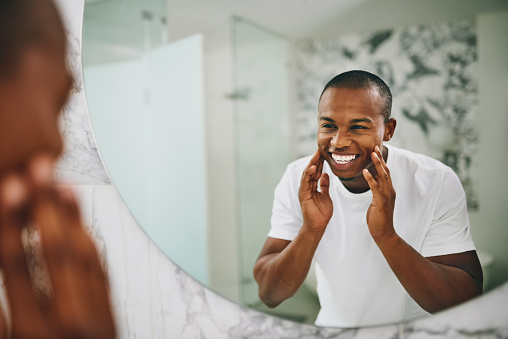 Shot of a young man going through his morning routine in the bathroom at home